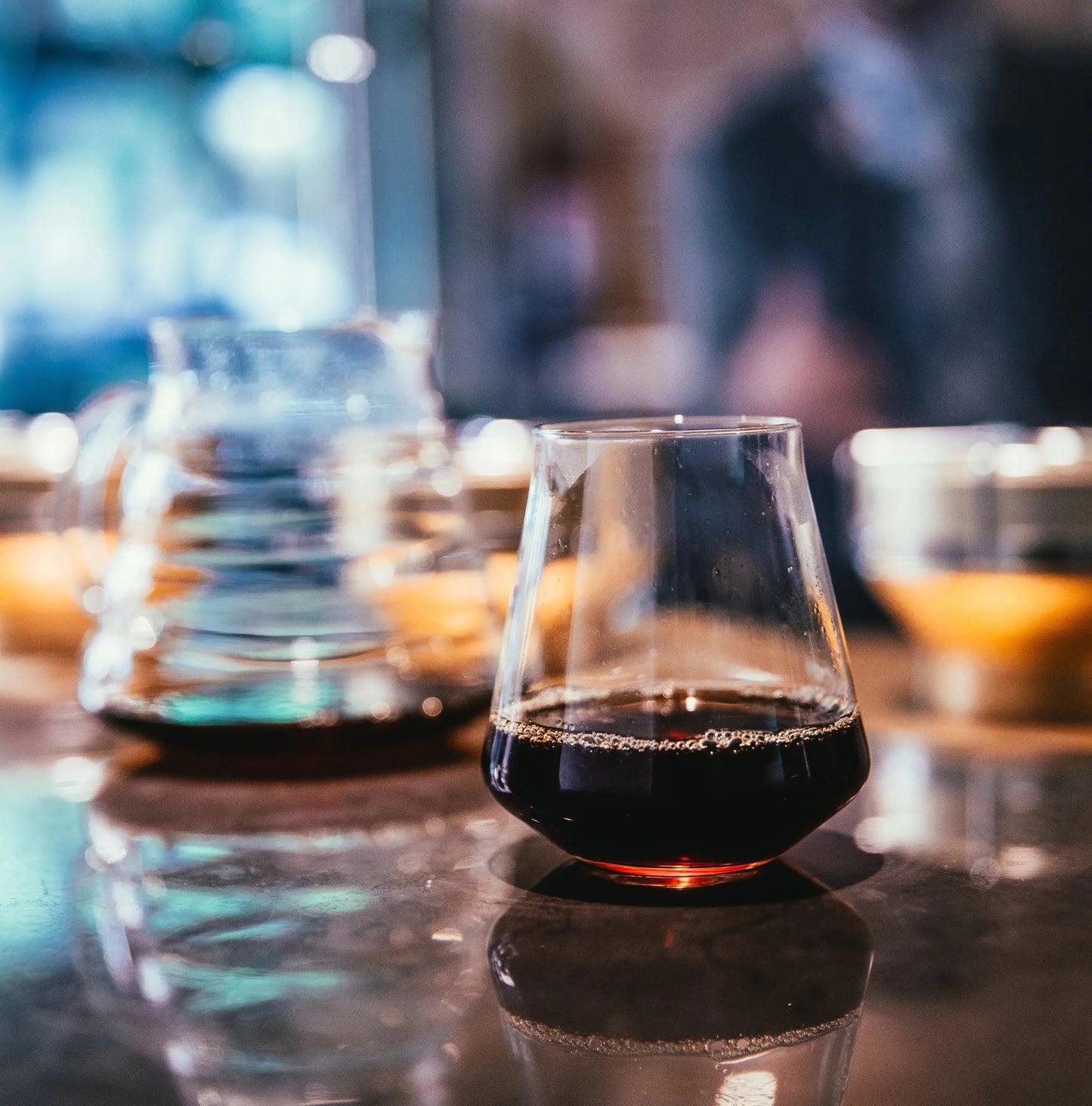 Glass with coffee pour over on a bar counter with blurred background